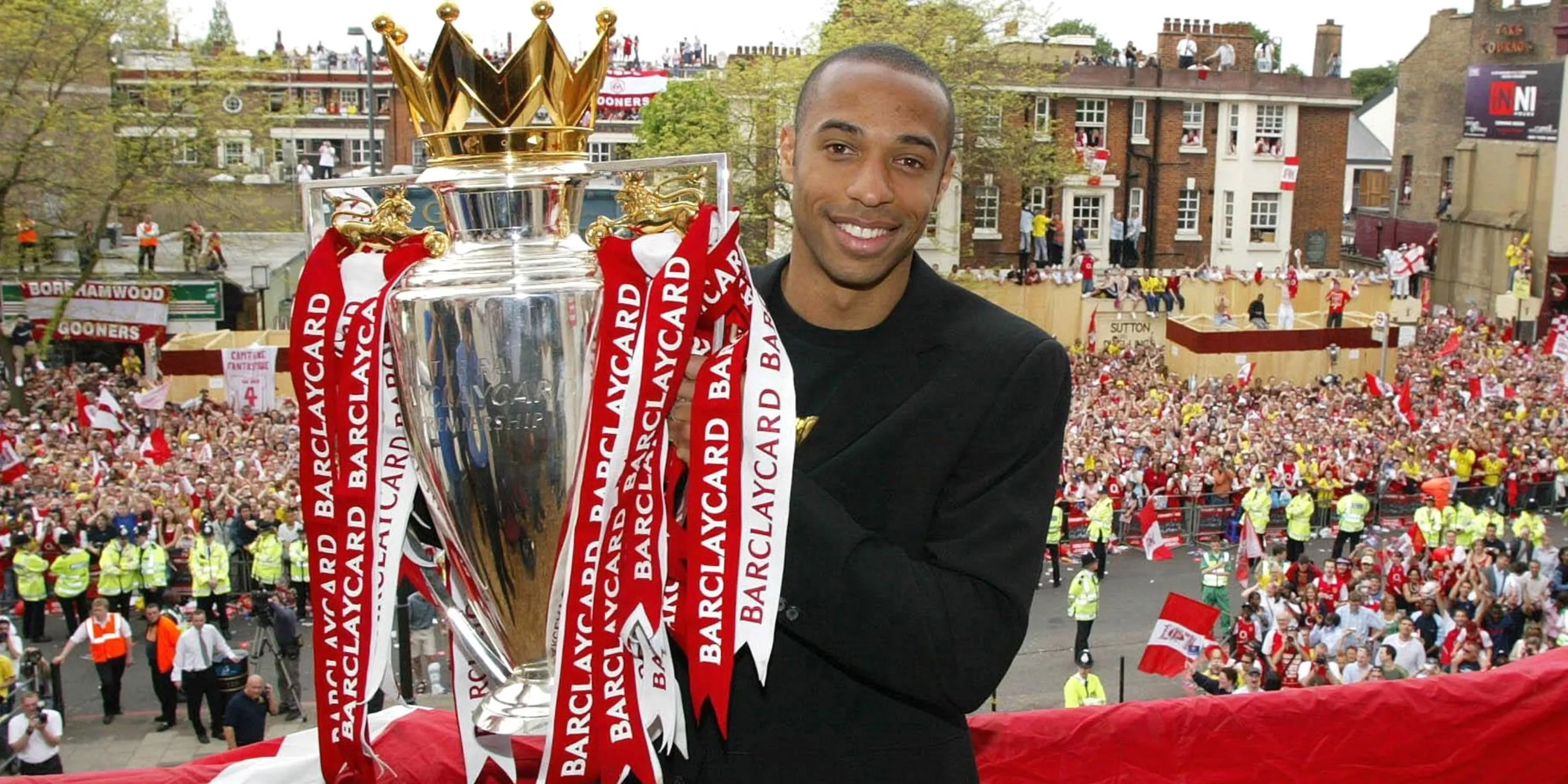 Huyền thoại Arsenal Thierry Henry bên cạnh chiếc cúp Premier League giành được năm 2004