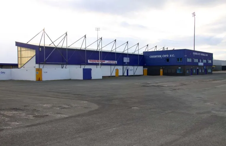 Cận cảnh bên ngoài sân vận động Deva Stadium, với lối vào chính và kiến trúc mặt tiền.