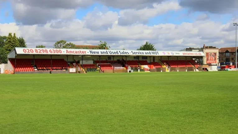 Khán đài chính có mái che với ghế màu đỏ tại sân Park View Road, sân nhà của Welling United.