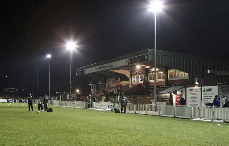 Khán đài Hayes Lane Stadium vào buổi tối, với ánh đèn sân lung linh và không gian tĩnh lặng